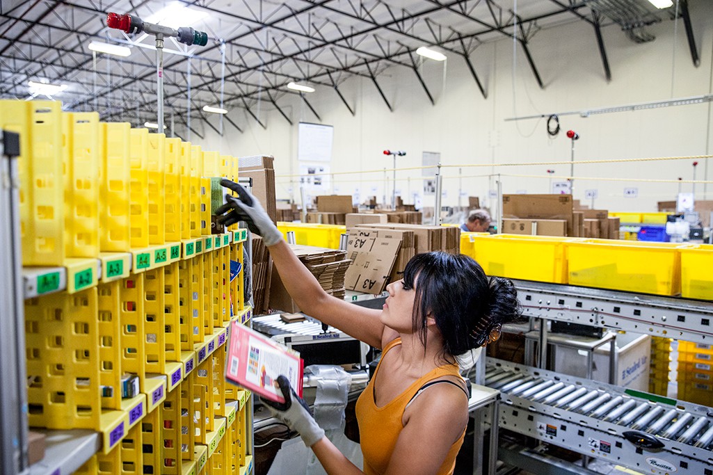 Сотрудница Amazon Ванесса Флорес достает товары из «мульти маленьких» ячеек, чтобы упаковать и пустить по конвееру для отправки