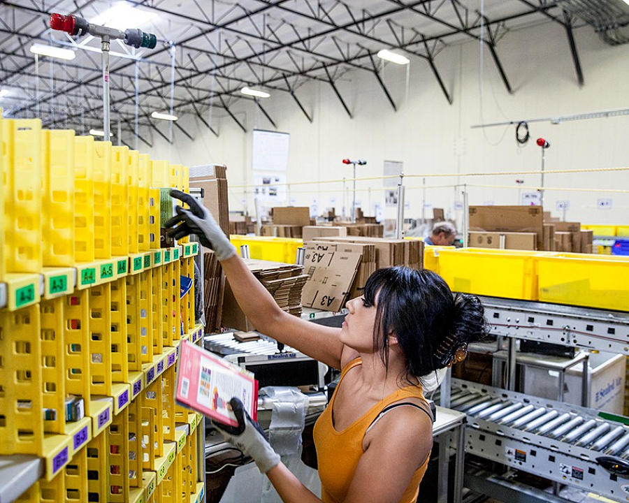 Сотрудница Amazon Ванесса Флорес достает товары из «мульти маленьких» ячеек, чтобы упаковать и пустить по конвееру для отправки
